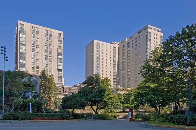 Exterior view of a multi-story senior living facility named Horizon House, surrounded by trees and greenery under a clear blue sky.