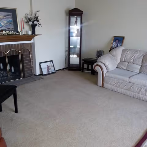 Cozy living room with beige sofa, fireplace, and framed photos.
