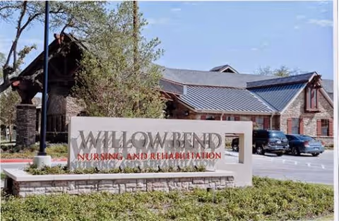 Stone entrance sign for Willowbend Nursing and Rehabilitation in front of the facility building with parked cars.