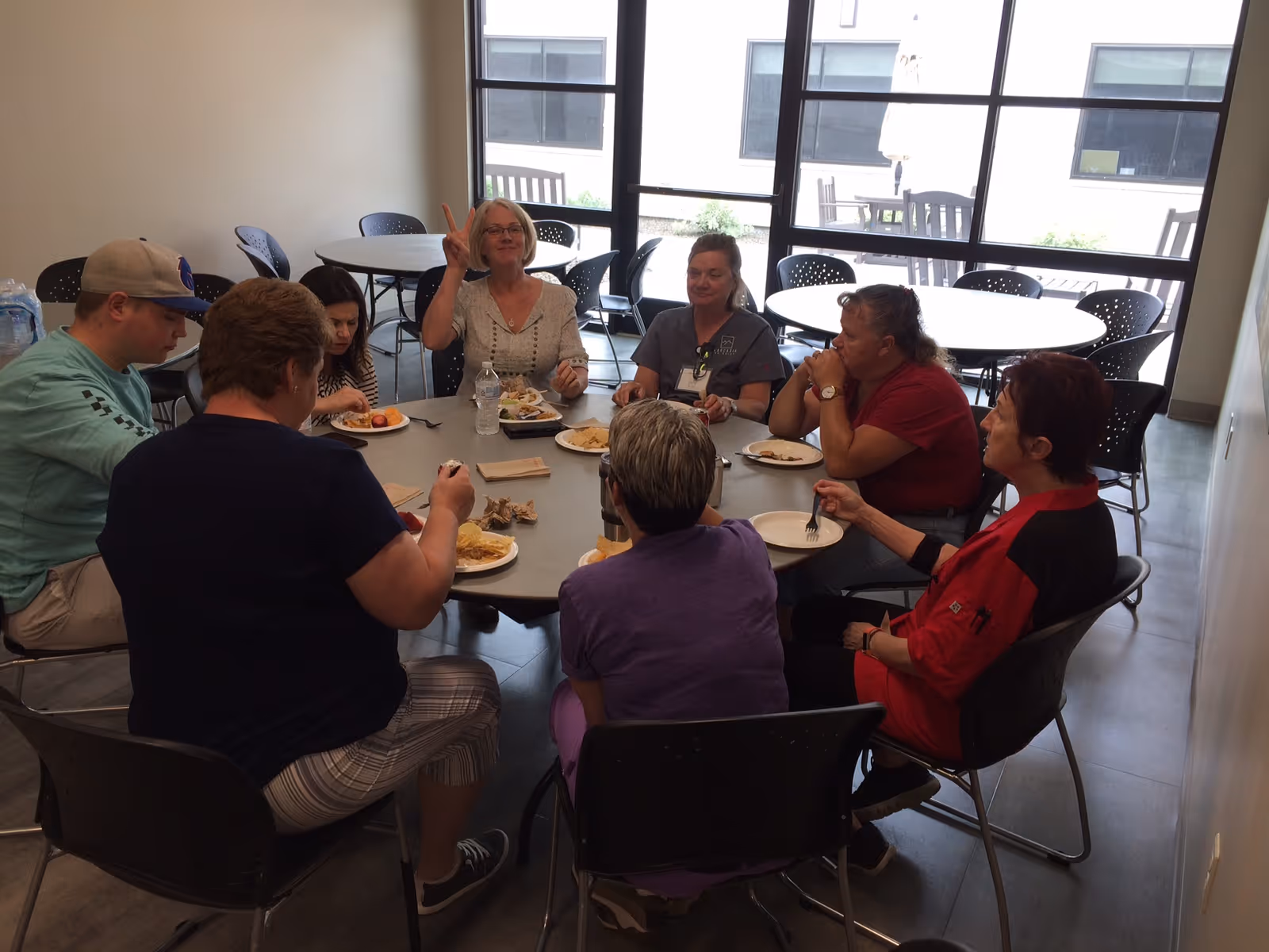 A group of people sitting around a round table in a communal dining area eating and talking.