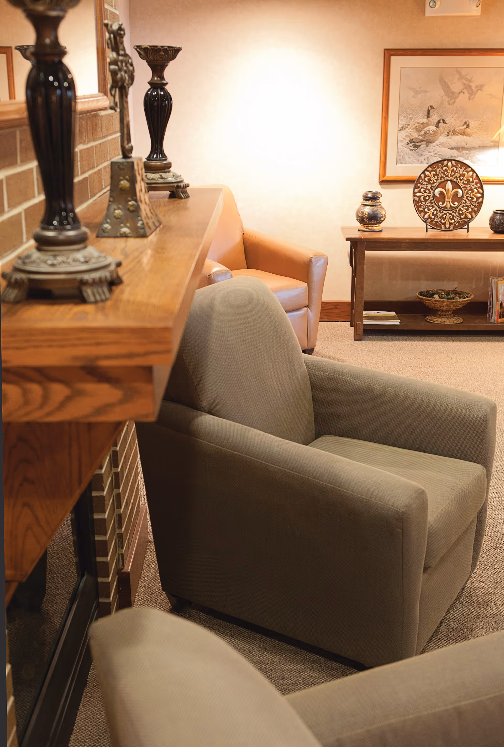 Upholstered armchairs arranged near a wooden mantel and a console table with decorative accents in a cozy seating area.