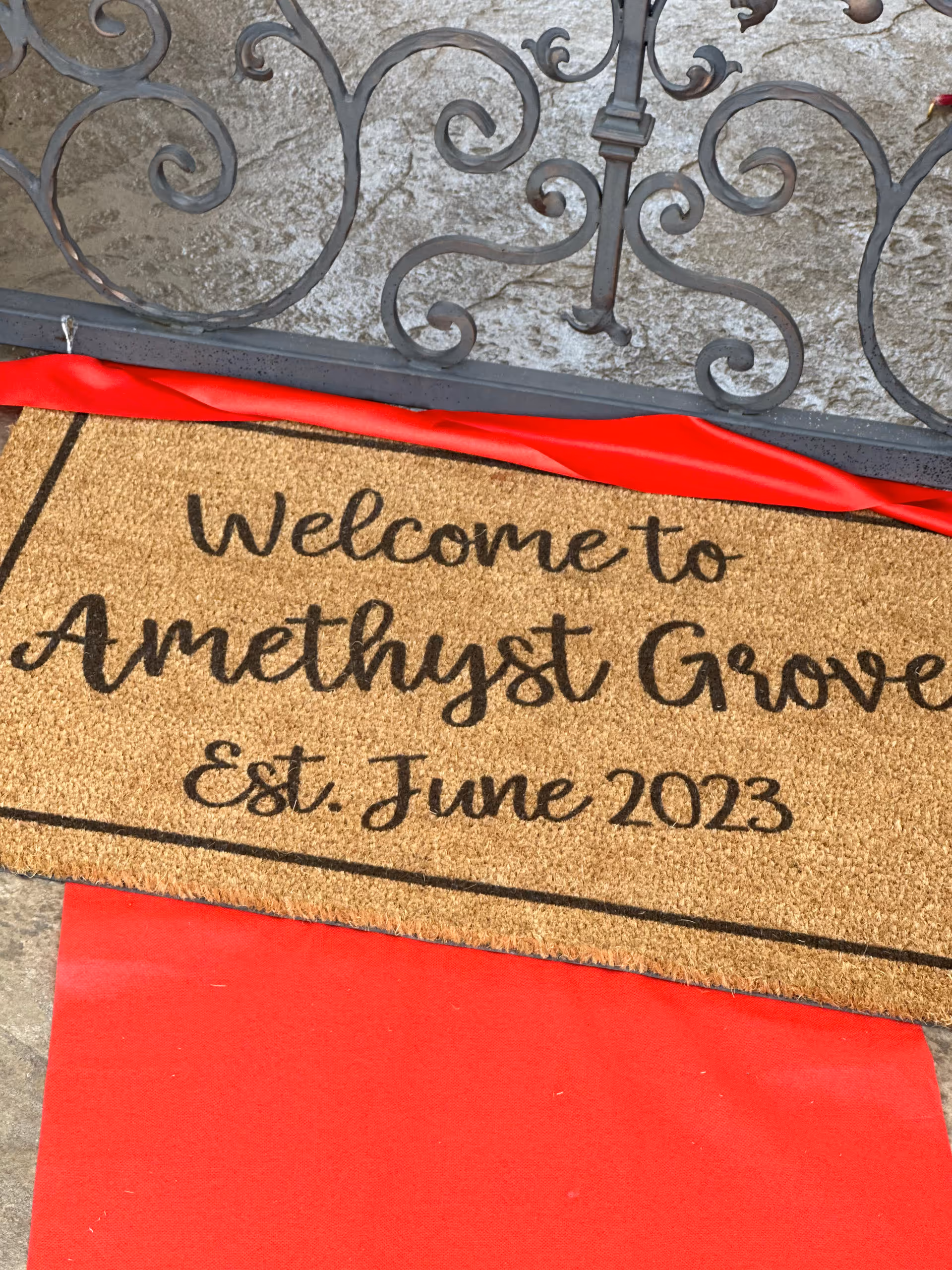 Welcome mat at the front entrance reading 'Welcome to Amethyst Grove' with decorative wrought-iron railing above.