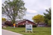 Lawn and entrance sign for Oakwood Specialty Care in front of a single-story red building with trees.