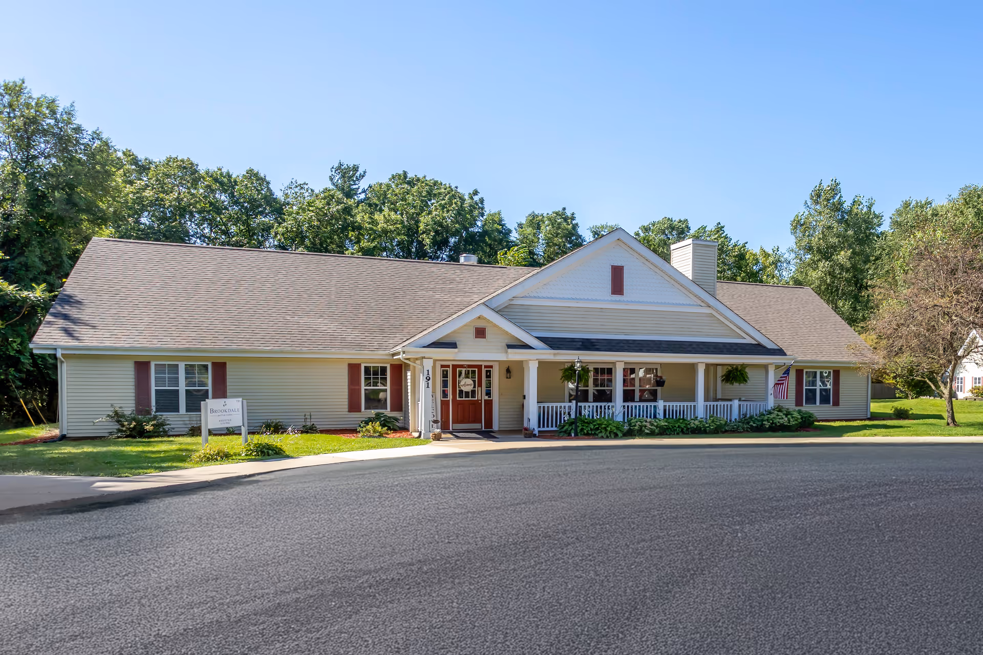 Single-story senior living facility with a front entrance, porch, and surrounding green lawn.