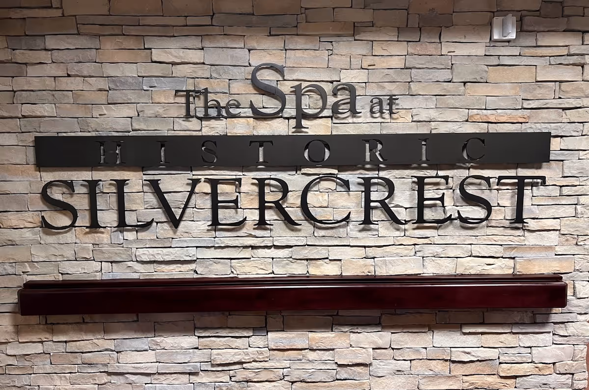 Wall-mounted metal sign reading "The Spa at Historic Silvercrest" on a stone veneer wall.
