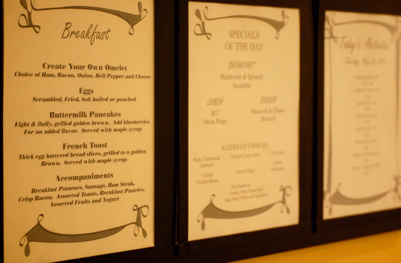 Three framed printed menus on a wall showing breakfast and daily specials.