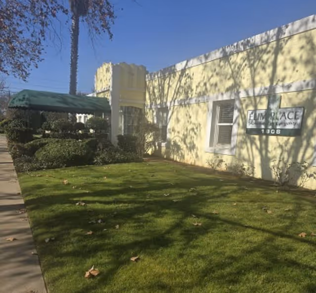 Exterior view of Elim's Place facility with yellow walls, lawn, and sidewalk.
