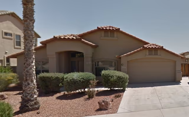 Front view of beige assisted living home with red-tiled roof and garage