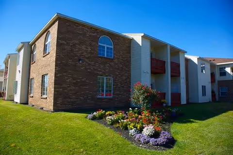 Exterior view of Brookdale Castle Gardens building with brick walls and landscaped front yard.