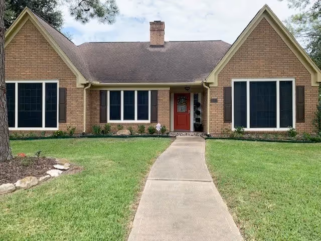 Front exterior of a brick assisted living facility with a red entrance door.