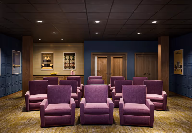 Interior screening room with three rows of purple upholstered recliner chairs facing a front wall with doors and framed posters.