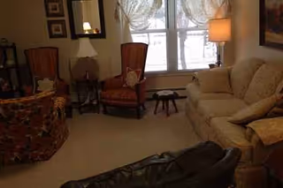Cozy living room in Riverfront Manor with beige sofa, armchairs, lamps, and a window.