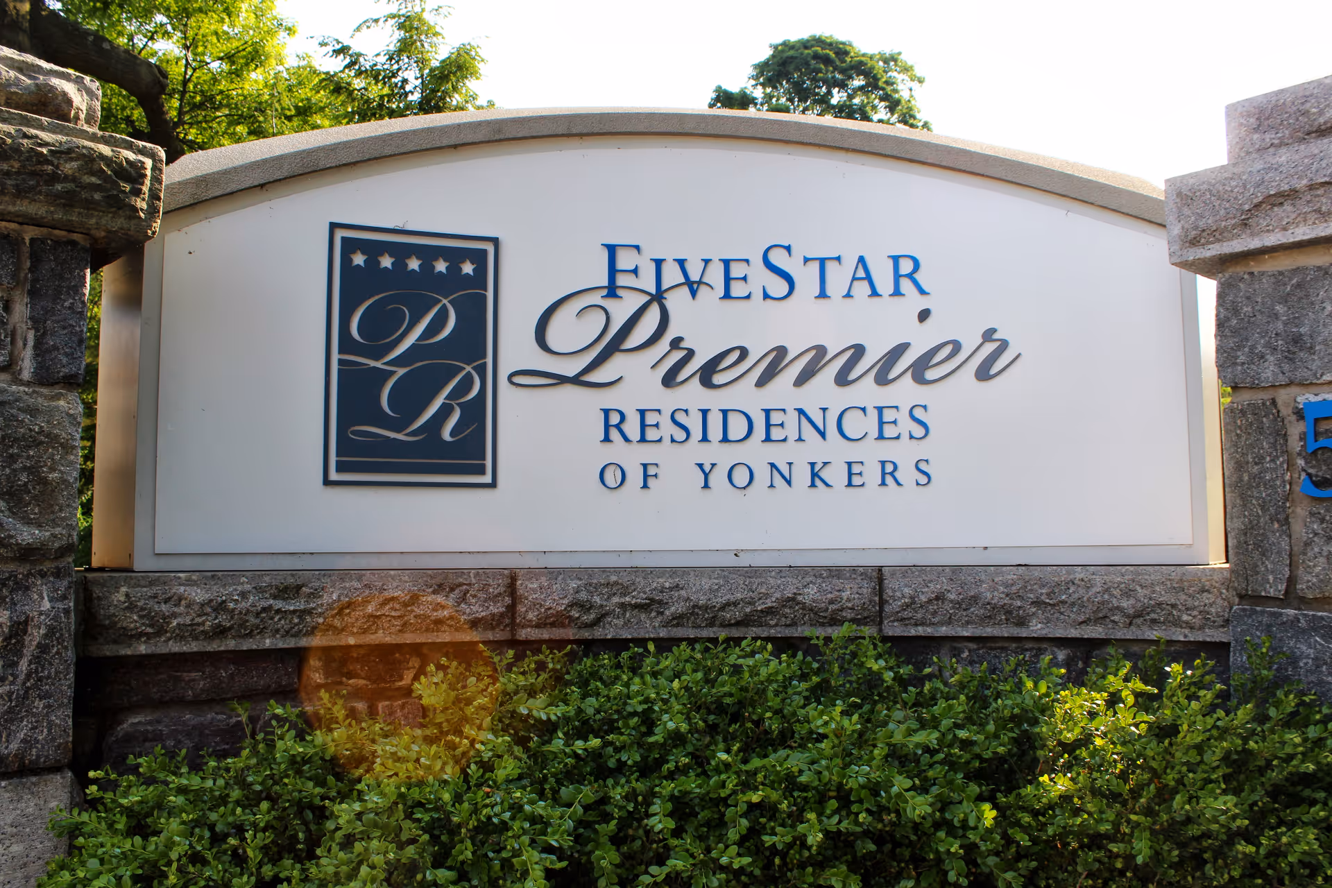 Outdoor sign for Five Star Premier Residences of Yonkers, mounted on a stone base with greenery in front and trees in the background.