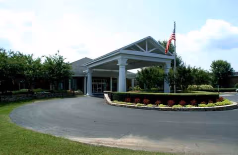 Tryon Estates front entrance with circular driveway, landscaped curb, and flag under a porte-cochere.