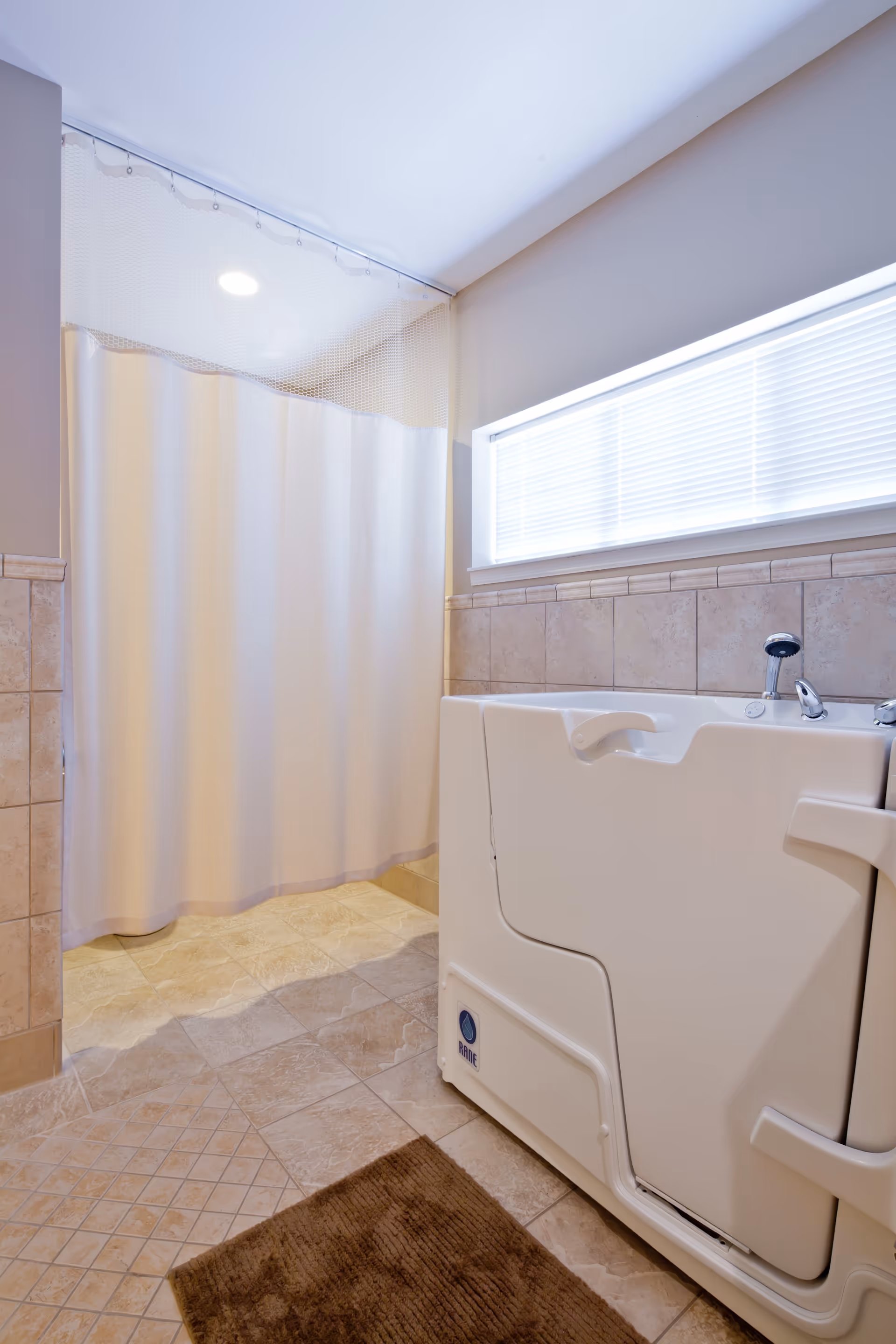 Accessible bathroom with a walk-in bathtub, shower curtain, tiled floor, and a frosted window.