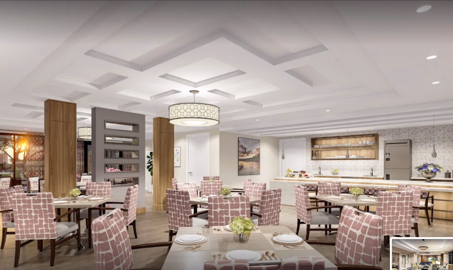A spacious and modern dining room with multiple tables and chairs featuring pink patterned upholstery. The room has a coffered ceiling with recessed lighting and a large decorative pendant light. There is a kitchen area in the background with a refrigerator, open shelving, and a countertop with various items. The walls are decorated with artwork and patterned tiles, and large windows allow natural light to enter the space.