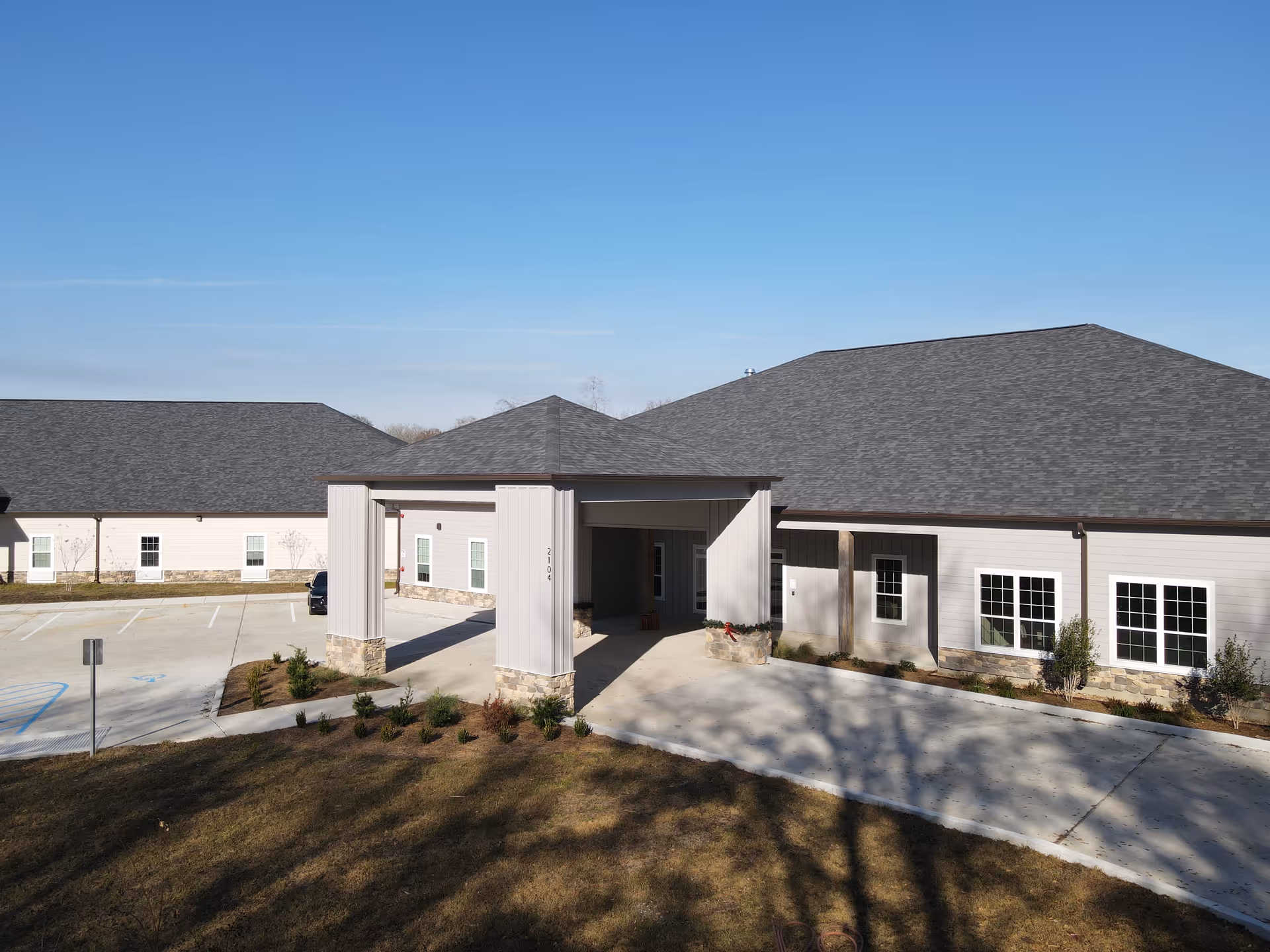 Exterior view of West Towne Assisted Living Community building with a covered entrance, multiple windows, and a parking area under a clear blue sky.