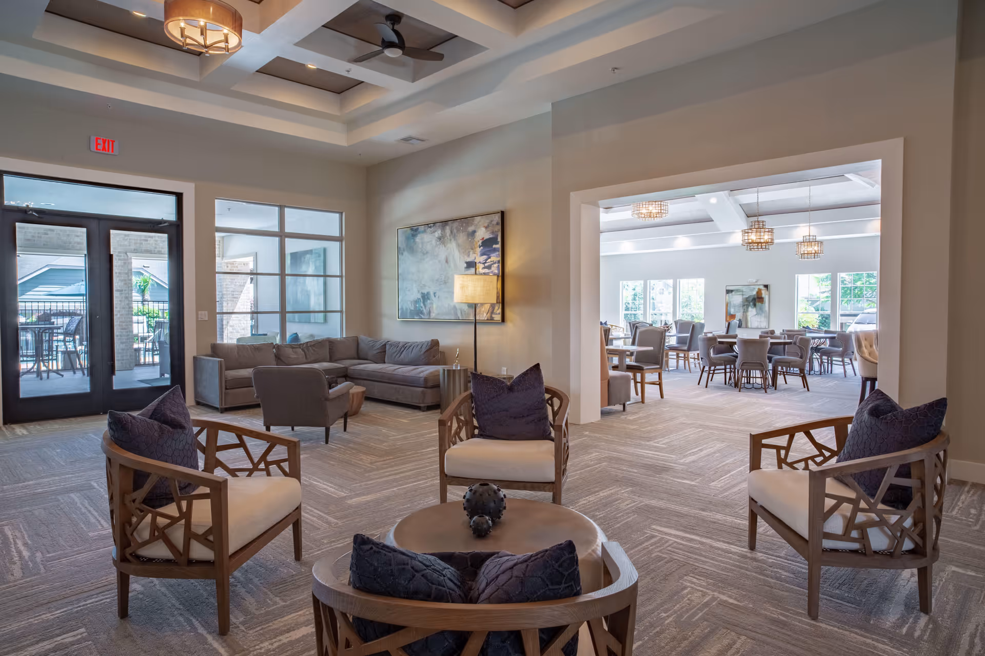 Spacious modern communal lounge with armchairs, a sectional sofa, and a view into a dining area.