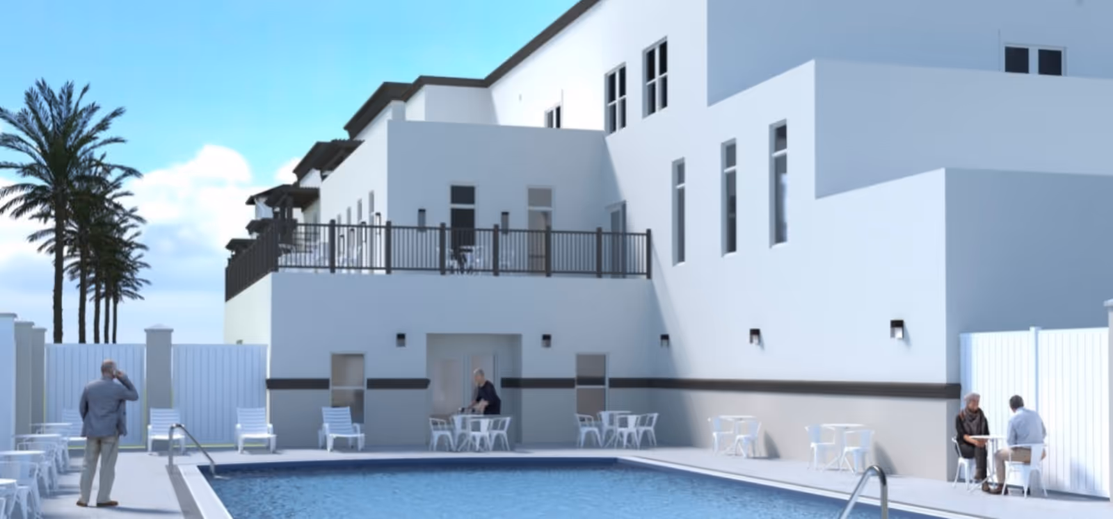 Outdoor pool area with a white multi-story building, lounge chairs, tables, and a few people around the pool.