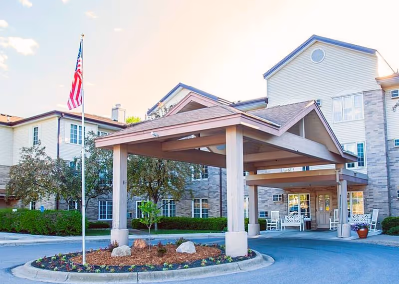 Exterior view of Elim Shores senior living facility with covered entrance, flagpole, and landscaped circle drive.