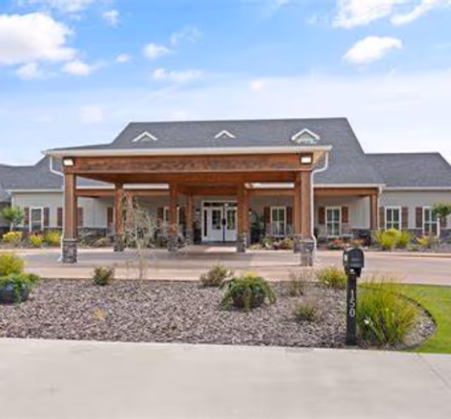 A senior living facility entrance with a covered porte-cochère and landscaped front yard.
