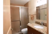 Small bathroom with a granite-topped vanity and sink, mirror, toilet, and a sliding glass-door shower.