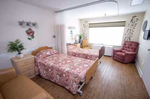 Two twin beds with floral bedspreads, bedside tables, and seating area in a bright bedroom.