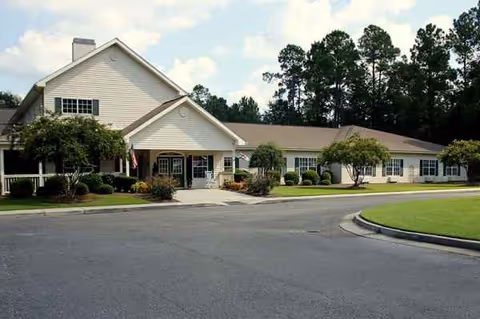 Beige single-story senior living center with front entrance and landscaped grounds.