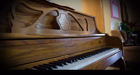 Close-up of a polished wooden piano in a cozy living room.
