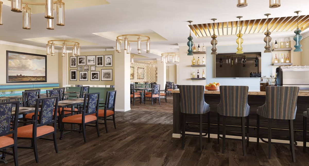 Spacious senior living dining area with tables and chairs, a bar with high stools, pendant lights, and a wall-mounted TV.