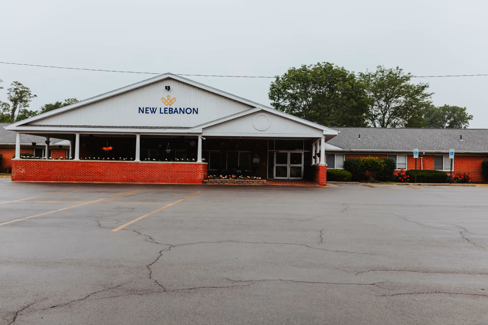 Front entrance of New Lebanon Rehabilitation and Healthcare Center, a single-story brick building with a covered entry and empty parking lot.