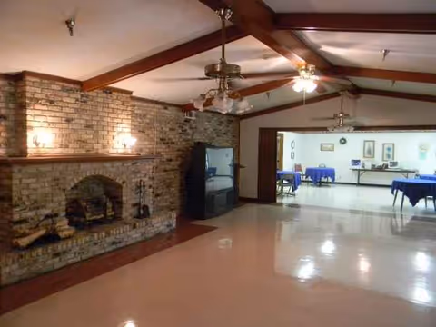 Interior common area with brick fireplace, exposed beams, and dining tables in the background.