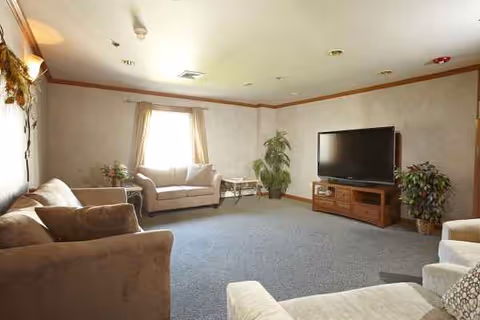 Cozy senior living room with sofas, plants, and a TV.