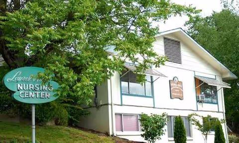 Exterior view of Laurel Hill Nursing Center building with sign among trees.