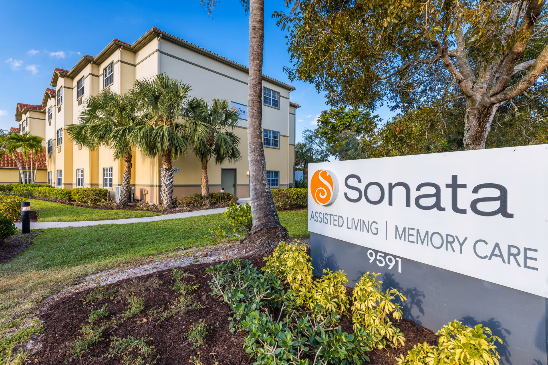 Exterior view of the Sonata assisted living building with landscaping and a large Sonata sign in the foreground.