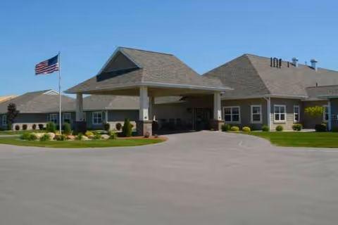 Exterior view of The Brook of Gaylord senior living facility with driveway, entrance, and American flag.