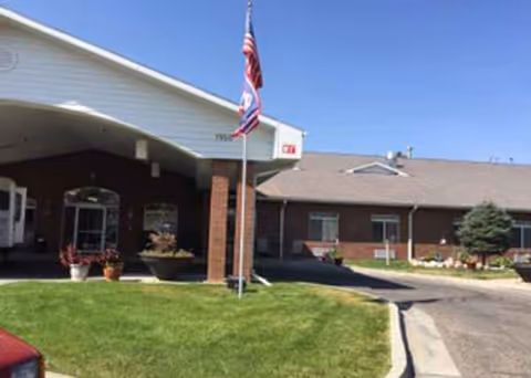 Front entrance of Garden Square Assisted Living of Casper with flags and curving entryway.