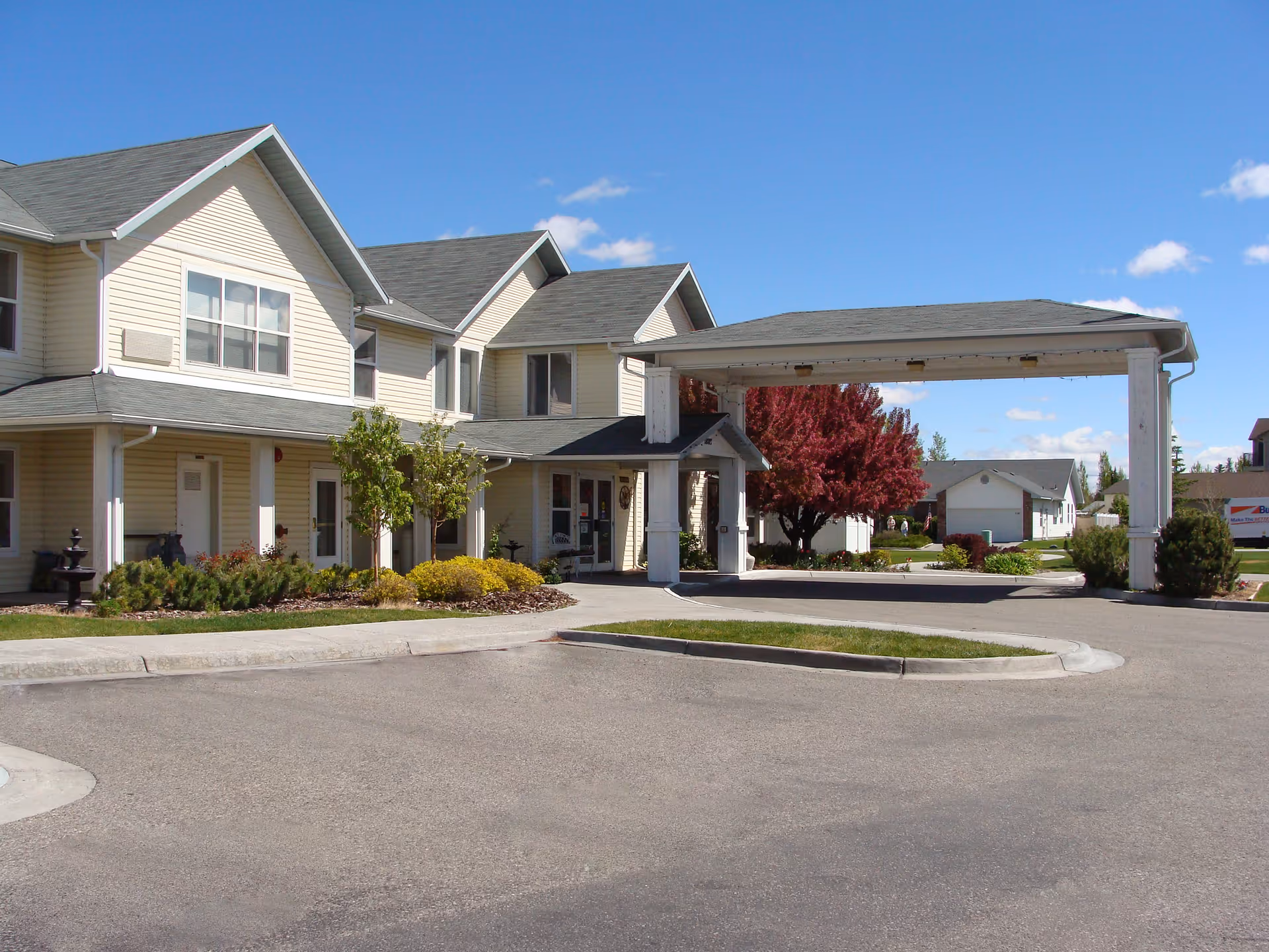 Exterior view of the Parkwood Meadows Assisted Living facility with trees and landscaping.