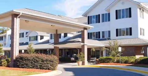 Exterior view of Monarch Estates senior living facility with covered entrance and landscaping.