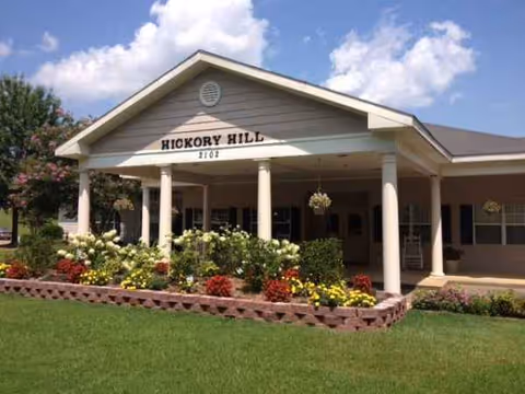 Front entrance of The Harbor at Hickory Hill with columns and flowering beds.