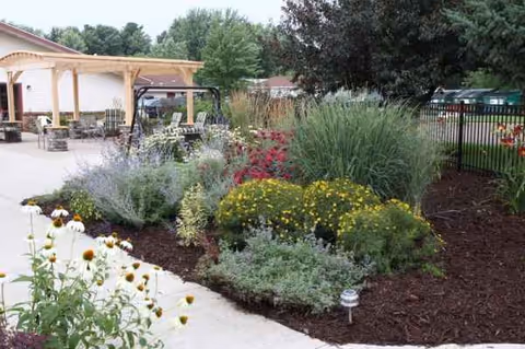 Outdoor garden and seating area of Oakbrook Health and Rehabilitation, with flowers and a shaded patio.