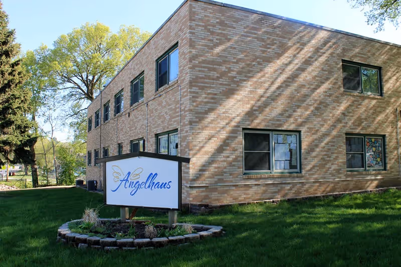 Exterior view of a brick senior living facility with Angelhaus sign in front