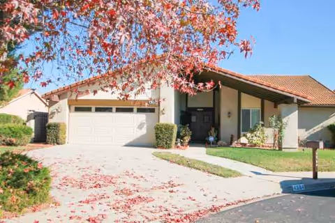 Front exterior of a single-story assisted living facility with a driveway and autumn leaves.