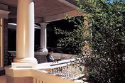Covered front porch of Heritage at Falmouth with columns, railing, and surrounding greenery.