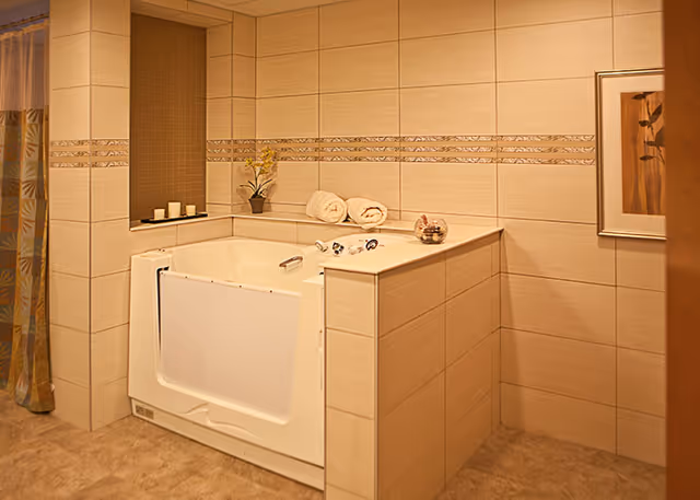 Walk-in bathtub with rolled towels, candles, and a shower curtain in a tiled bathroom.