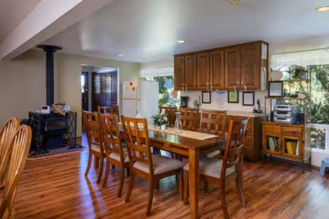 Dining room in a senior living facility featuring a long wooden table and cabinets.