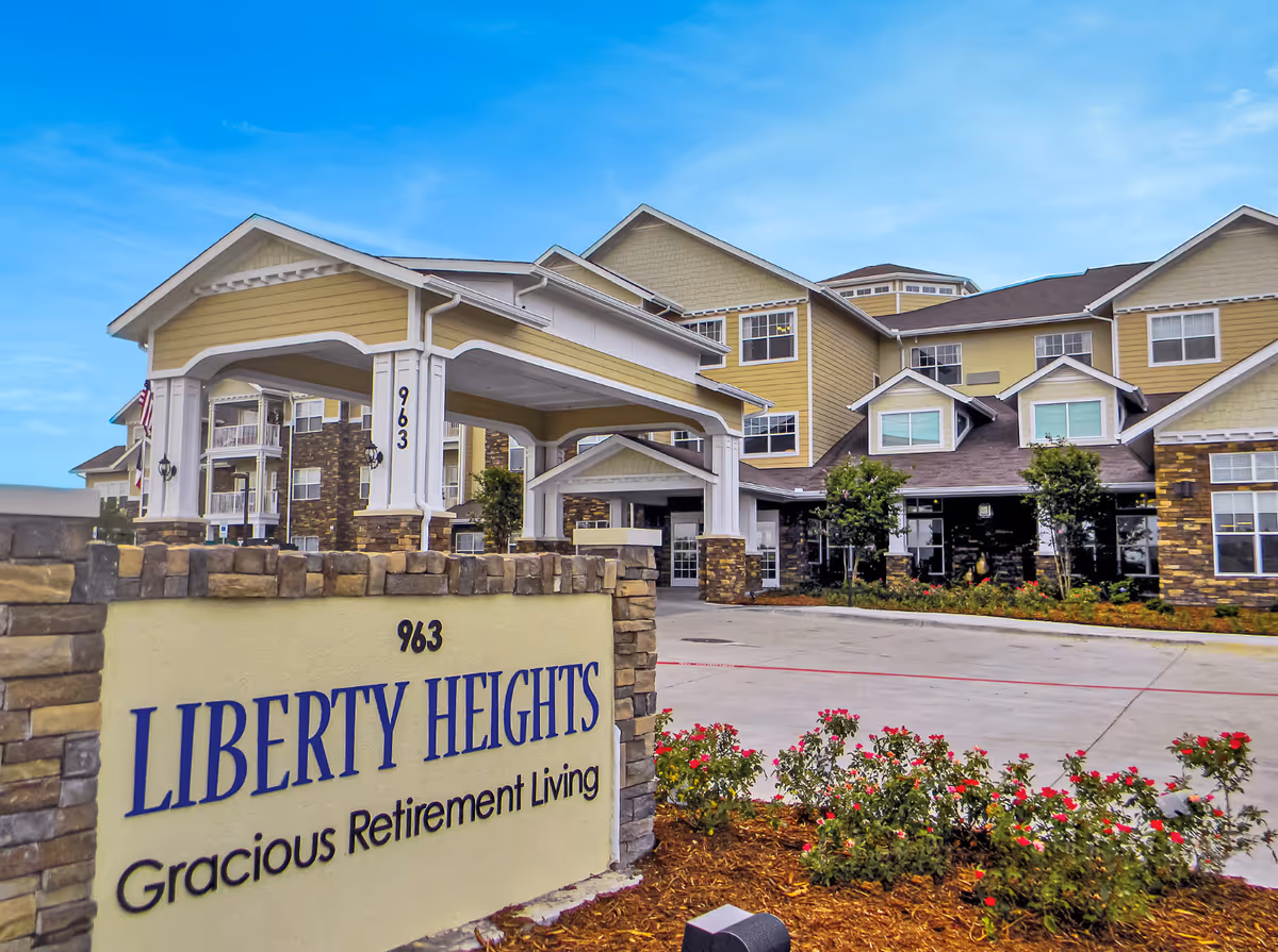 Front exterior of a multi-story senior living building with a porte-cochère and a sign reading 'LIBERTY HEIGHTS Gracious Retirement Living'.