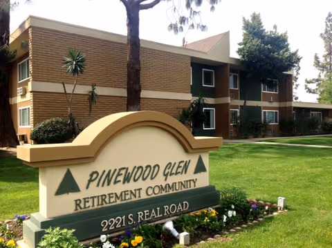 Pinewood Glen Retirement Community sign in front of brick building and green lawn.