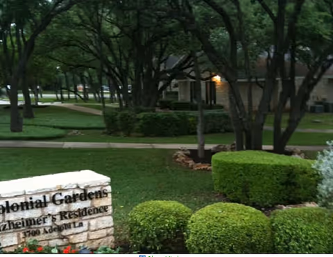 Exterior view of Colonial Gardens of Austin with trees and a stone sign.