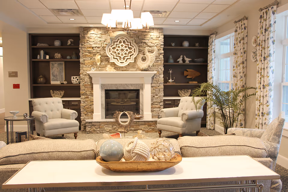 Comfortable living room with a stone fireplace flanked by built-in shelves, upholstered chairs, a sofa, and decorative accents.